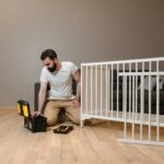 A man assembling a white crib indoors with tools, focusing on DIY and home care.
