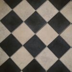 Diagonal black and white checkered floor tiles with a geometric design.